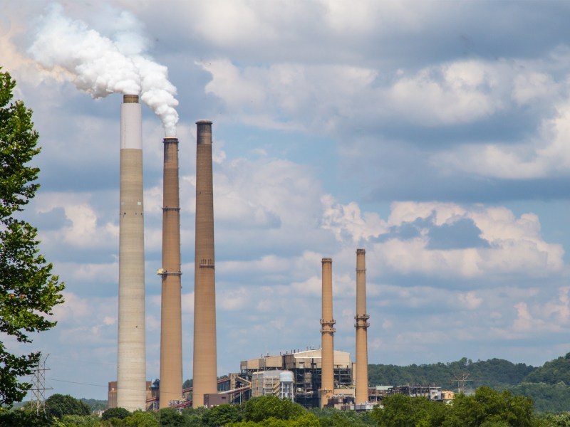 The Conesville, Ohio coal power plant features three large smokestacks set against a blue sky.