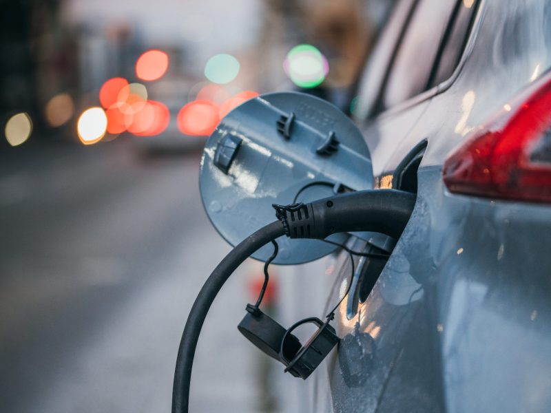 An electric vehicle charges on a street.