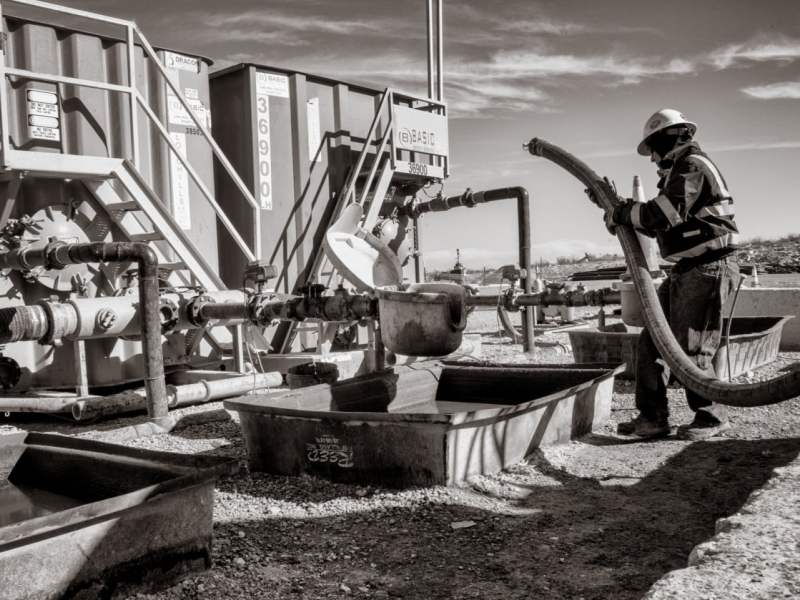 An oil worker carries a pipe.