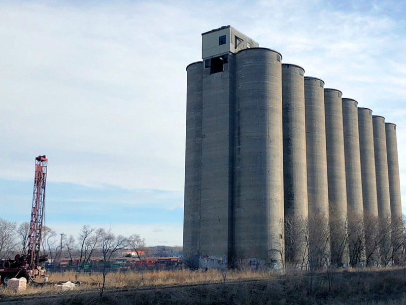 A group of grain silos tower over a drilling rig in Minneapolis.