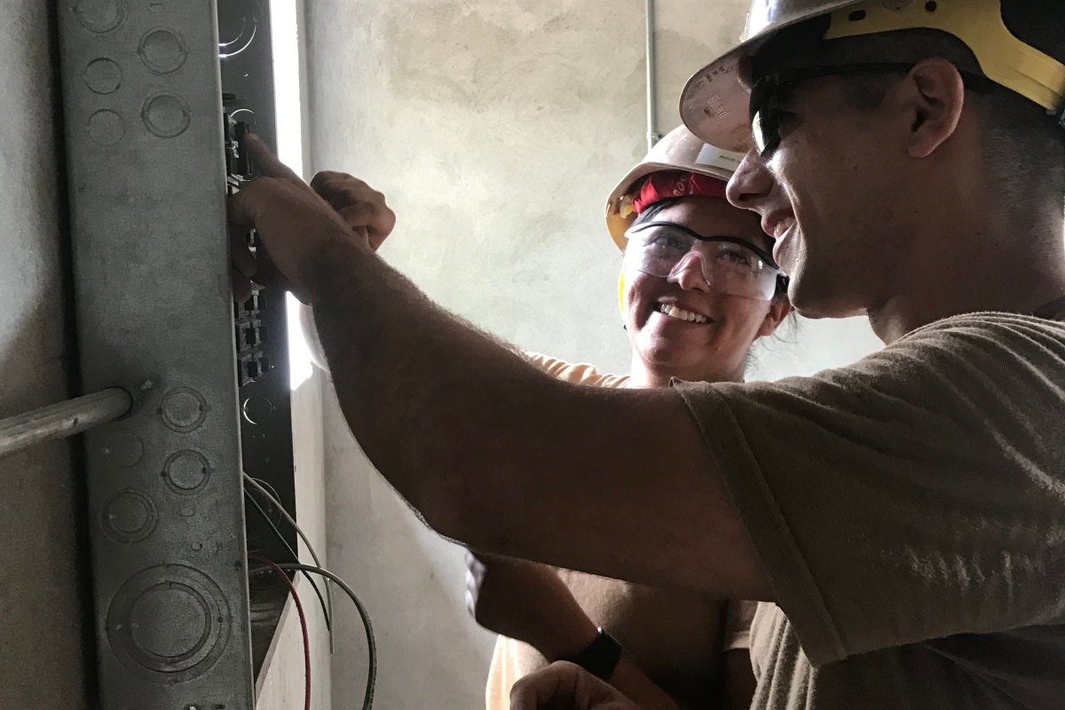 Electricians work on a breaker panel