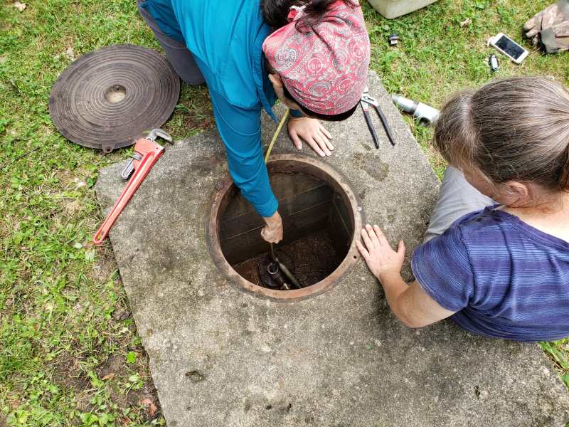 Geologist Andreana Madera-Martorell reaches into a groundwater well.