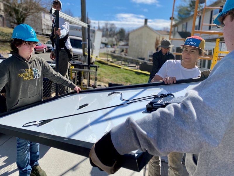 Virtue Solar operations manager Kim Monge Fera, center, directs high school classmates Ashton Wisecarver, left, and James Jackson as they hoist a solar panel in Warrenton, Virginia.