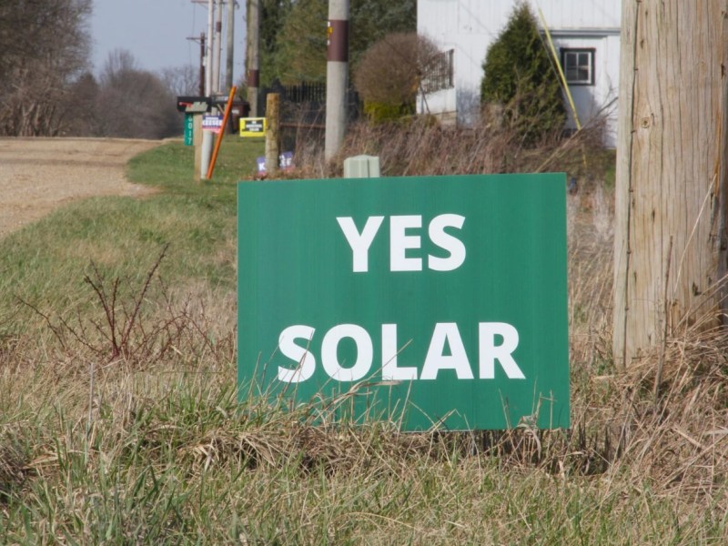 A green sign yard sign with the words "Yes Solar" on a rural road in Knox County, Ohio.