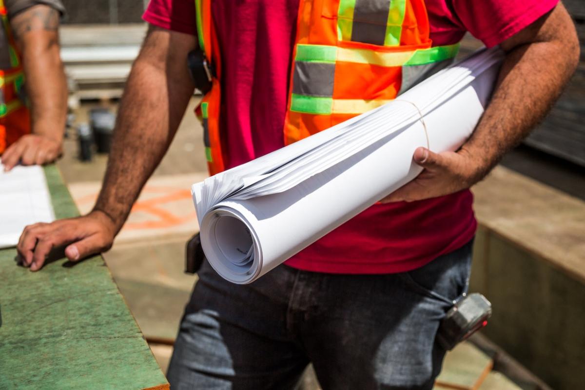 A person holding a roll of drafting paper