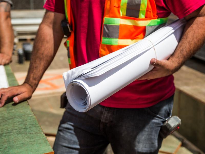 A person holding a roll of drafting paper