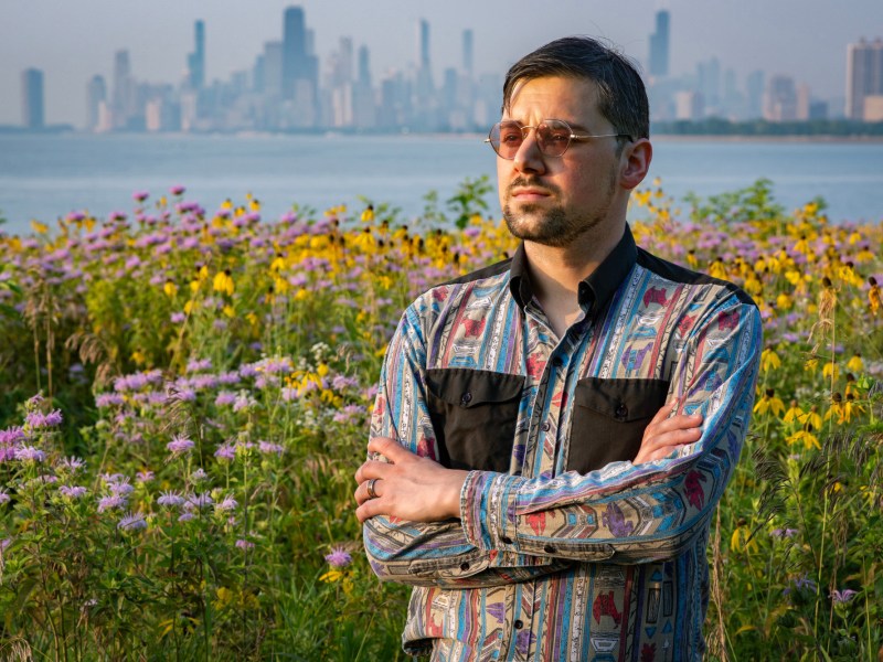 Saxon Metzger stands in a field of wildflowers with the Chicago skyline in the distant background.