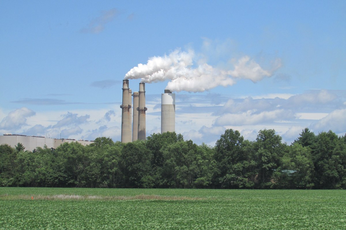 Smokestacks at the R.M. Schahfer Generating Station appear behind a line of trees and a field