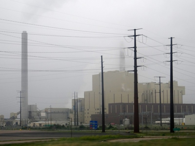 A power plant on a foggy day with transmission lines in the foreground.